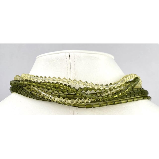 Mid Century Multi strand necklace featuring alternating green and clear beads crafted from glass. The necklace showcases a...