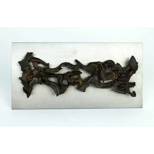 Abstract sculpture in patinated metal, fixed on a steel plate, unsigned, France. The dynamic assembly of the cut, striated...