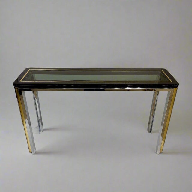 Architectural console table with faceted legs in chrome and brass, supporting a black lacquer framed top with glass inset...