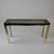 Architectural console table with faceted legs in chrome and brass, supporting a black lacquer framed top with glass inset...