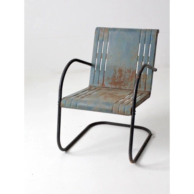 This is a mid-century metal bouncer chair featuring a classic patio design. The chair has a blue bouncer-style frame and a...
