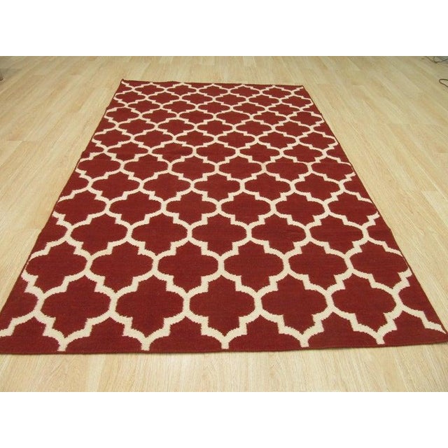This 8 x 10 feet wool rug features a flat weave construction in a primary color palette of coral, salmon, and pink....
