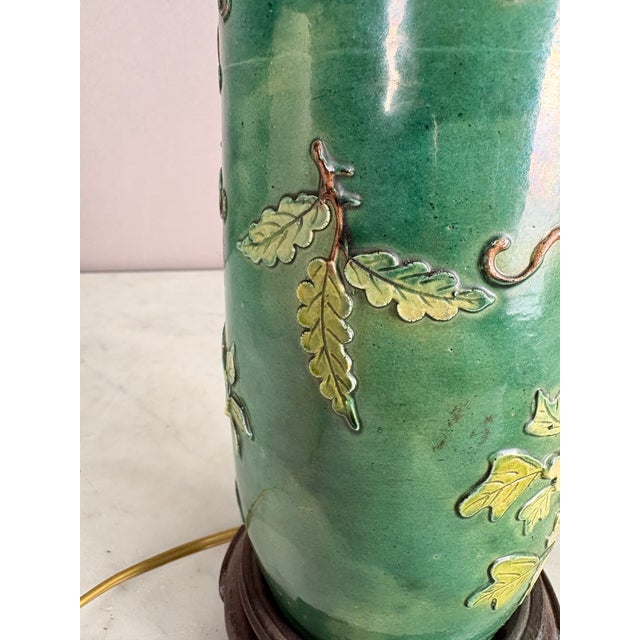 This gorgeous green glazed table lamp has a raised flower design with leaves and vines. Attached is a wooden base and...