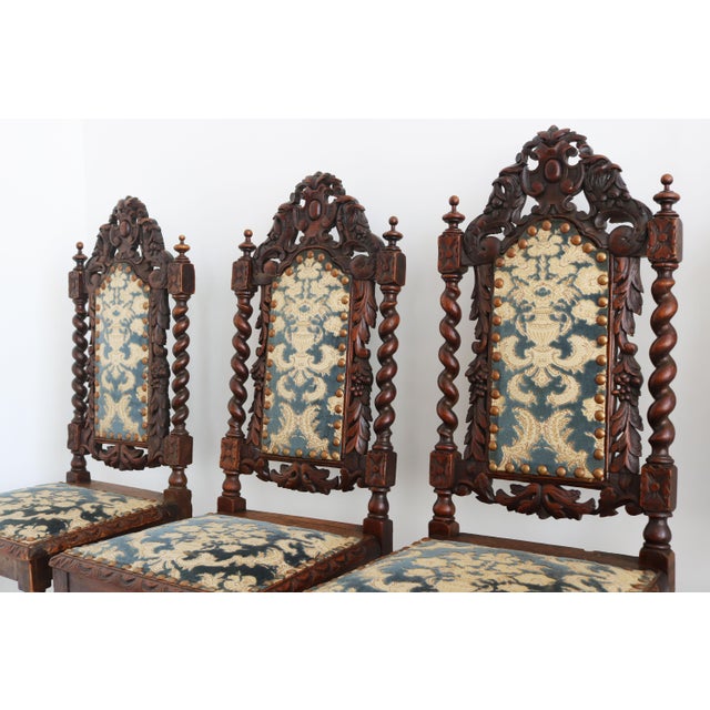A striking set of four late 19th-century Renaissance Revival dining chairs, masterfully handcrafted from solid oak and...