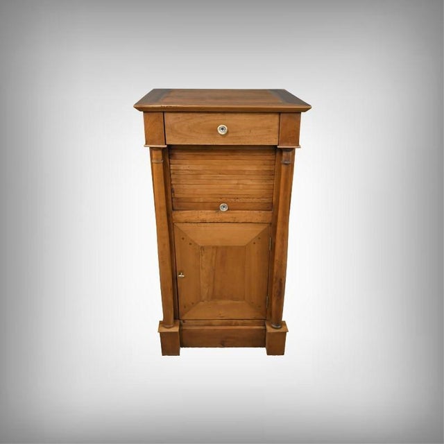 This small cherrywood cabinet, typical of the Empire style, boasts a slender and harmonious silhouette where architectural...