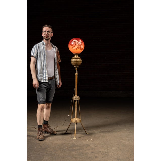 This ornate floor lamp features a cast metal tripod base with twisted rods, acanthus leaf detailing, and claw feet, topped...