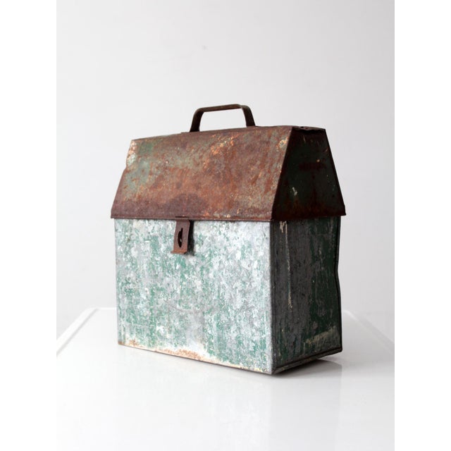 Mid-century galvanized metal toolbox with an old green-painted finish, pitched hinged lid, metal carrying handle, and...