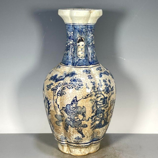 A striking Chinese blue and white porcelain vase featuring a heavy, all-over crackle glaze. The vase has a baluster shape...