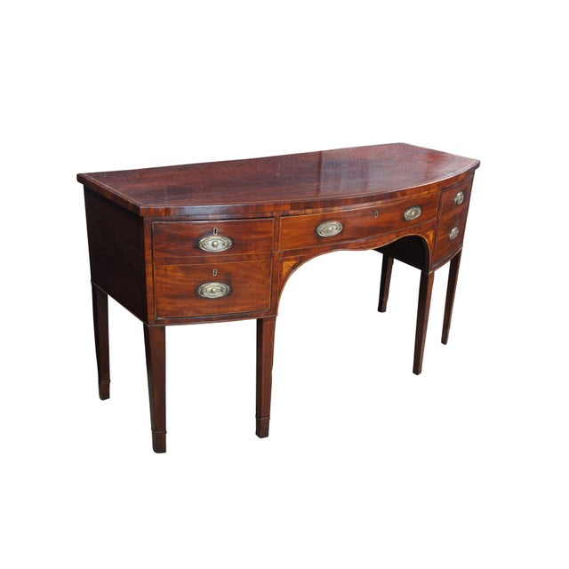 Late 18th Century George III Period Bowfront Sideboard. Features a mahogany framed case with cross banding, inlay and...
