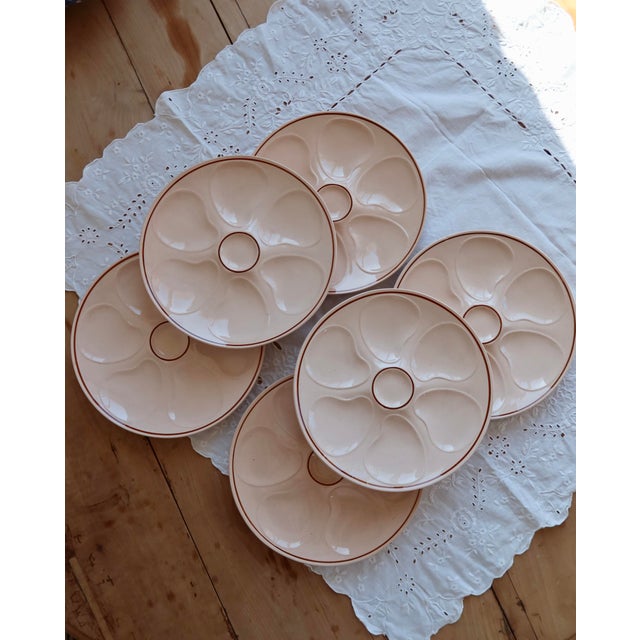 A delightful set of six Longwy pink earthenware oyster plates, featuring a delicate, powdery color and a timeless design....