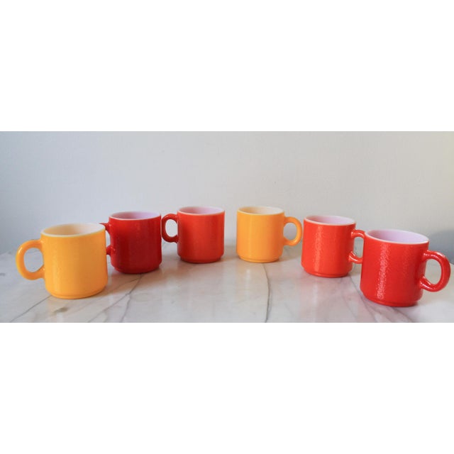 Set of six vibrantly colored, stackable milk glass mugs with an orange peel texture. Red, yellow and orange. No makers...