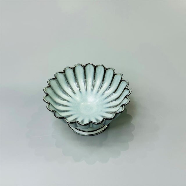 A pair of ceramic pedestal dishes with a chrysanthemum-petal rim; suitable for serving snacks or fruit, or for use as a...
