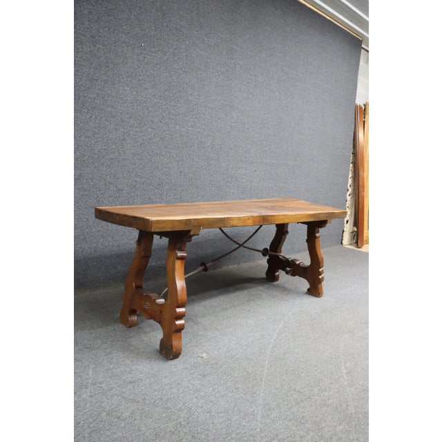Spanish style dining or console table with iron and trestle base. Walnut slab top with pine base.