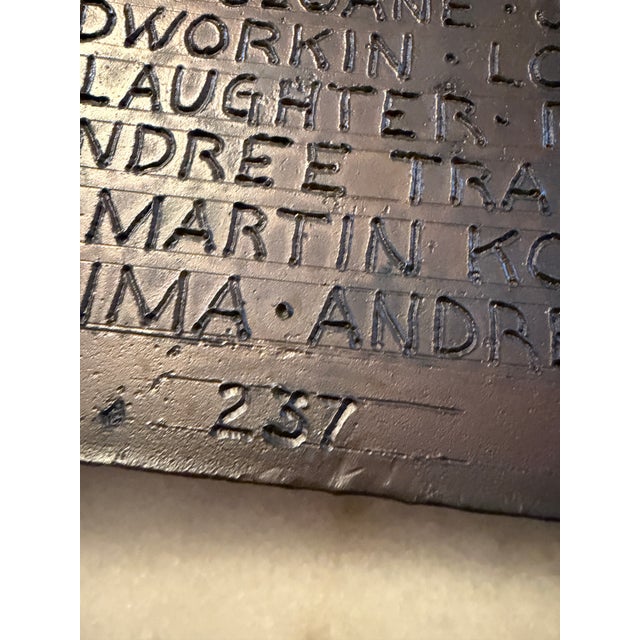 Name Recognition is a bronze sculpture in the form of an open book. Its two pages are etched with a list of artists’ names...