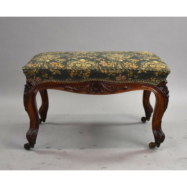 A fine antique upholstered footstool, showcasing quality craftsmanship and elegant period design. The generously padded...