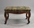 A fine antique upholstered footstool, showcasing quality craftsmanship and elegant period design. The generously padded...
