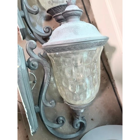 An elegant matched pair of wall sconces with ornate brass-finish candelabra bases and large glass urn-style shades....