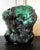 A natural malachite rock specimen with striking green and black colors fitted on a wood stand for viewing and meditating....
