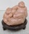 Happy Buddha /Hoti with one attendant, seated on a lotus leaf with his bag of wealth. A Chinese stone carving in a treated...
