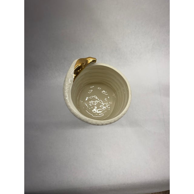 Striking white glazed porcelain vessel featuring a continuous coiled snake design with textured scaling. Finished with...