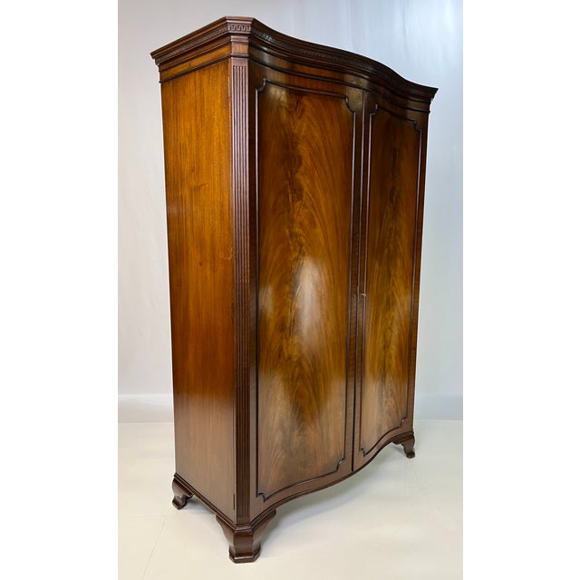 George III style serpentine front wardrobe armoire, crafted in rich, highly figured flame mahogany. This impressive piece...