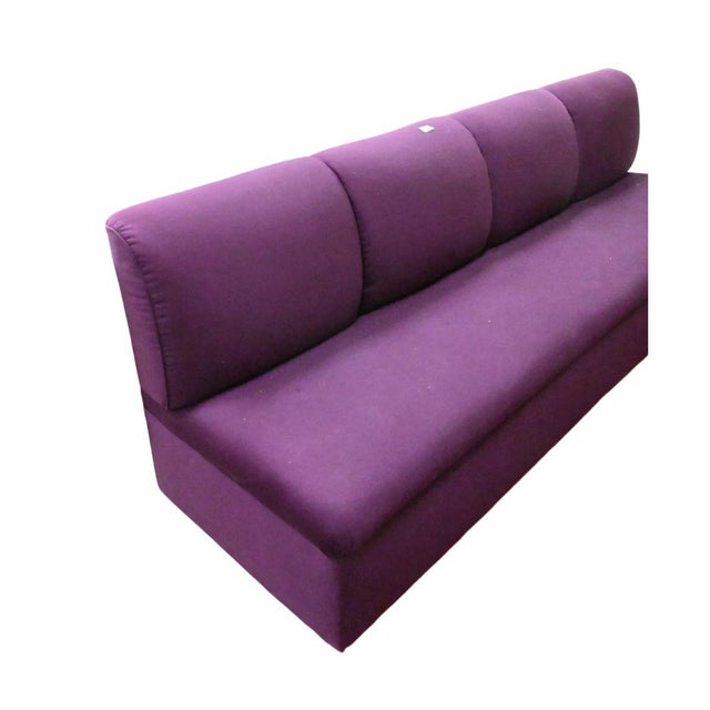 An upholstered aubergine banquette with tight four cushion back and bench seat. Sits on chrome base. Stains to fabric.
