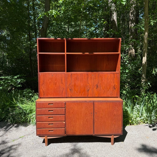 A versatile Danish Modern two-piece teak storage cabinet that combines open shelving, concealed storage, and a built-in...