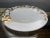 A delicate white porcelain dinner plate adorned with hand-painted gold flowers, by Philippe Deshoulieres for De Limoges...
