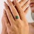Crafted in 925 sterling silver, this minimalist ring features a stunning 7x5 mm oval emerald paired with a 1.5 mm round...