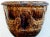 A handsome French brown-glazed anduze pot; the gadroon lip above a cup-shaped bowl adorned with 4 masks joined by plump...