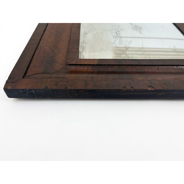 An authentic 19th-century American Empire Ogee wall mirror featuring richly figured flame mahogany veneer. The frame...