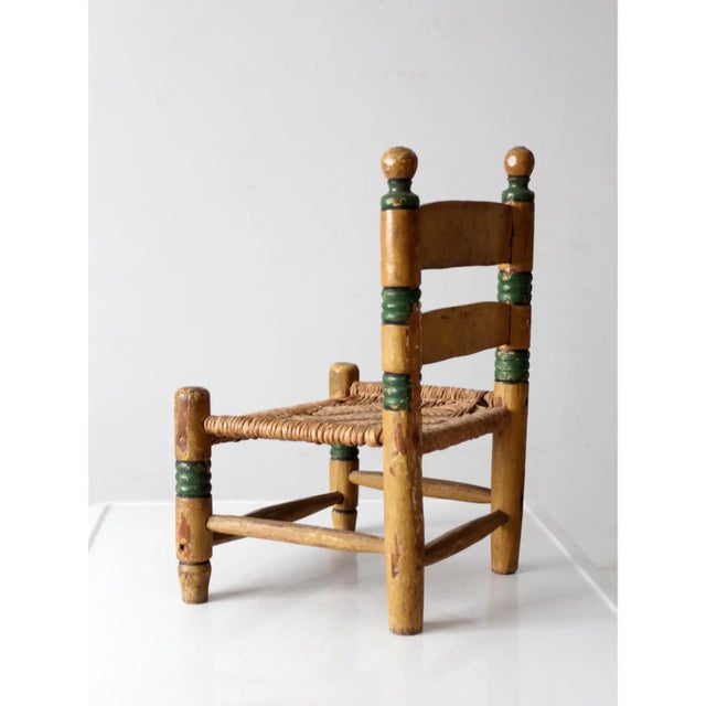Vintage Mexican folk art child’s chair featuring hand-painted floral details in mustard yellow and green. The wooden frame...