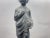 Decorative statue depicting a young child holding drapery and a floral motif, mounted on a square plinth with a carved...