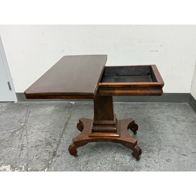 Design Plus Gallery presents a Victorian Regency Style Lift-Top Game Table. This antique table showcases a rectangular...