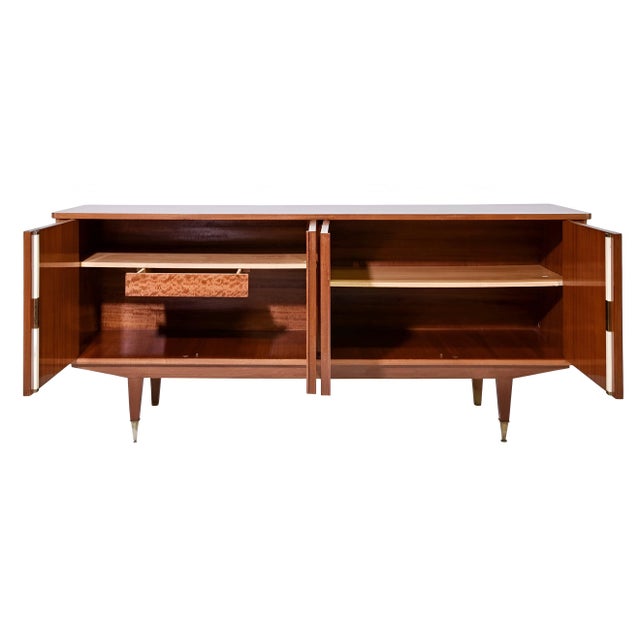 This mid-century modern lacquered wood sideboard features a clean-lined silhouette and a warm, light teak wood finish with...