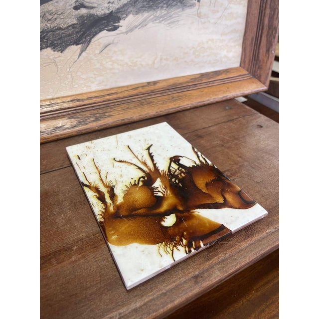This tile is white and brown toned paint or glaze on top of a ceramic tile. Wall hook in the back for hanging. Vintage...