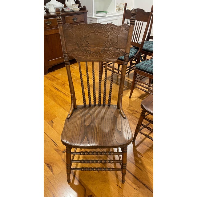 Highly stylish set of 8 antique oak American press back spindle chairs from the early 20th Century. The set is comprised...