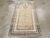 A vintage Turkish Anatolian throw rug. An austerely unadorned warm beige niche field is flanked and bottom bordered by a...