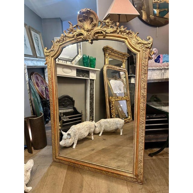 A large antique Louis XVI style Gold Gilt over mantel or fireplace mirror. Warm aged gilt, with some red bole showing. The...