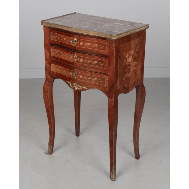 A Louis XVI style marble top marquetry nightstand, or side table, made of veneers of mahogany, walnut and exotics woods...