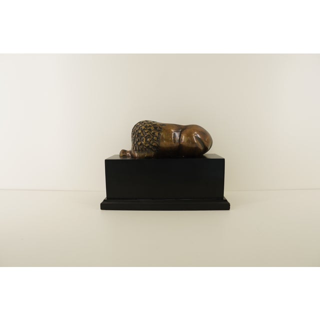 This sculptural decorative piece features a recumbent sleeping lion rendered in a bronze-toned metal finish, resting atop...