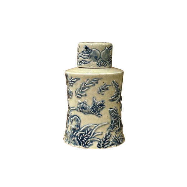 This exquisite ceramic jar features a classic blue-and-white relief design showcasing traditional motifs of swimming fish...
