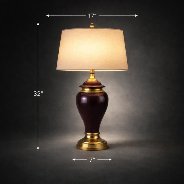 A striking 32” tall Hollywood Regency table lamp featuring a glossy eggplant ceramic body and polished brass accents....