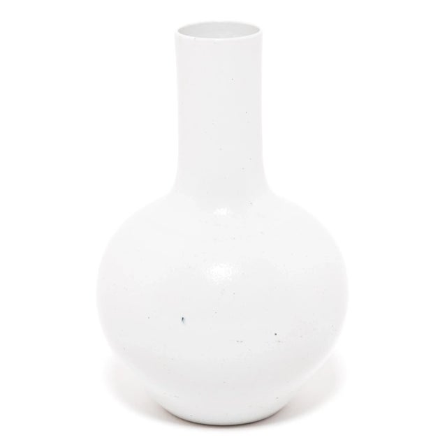Drawing on a long Chinese tradition of ceramics, this striking long-necked vase is cloaked in an all-over milky white...