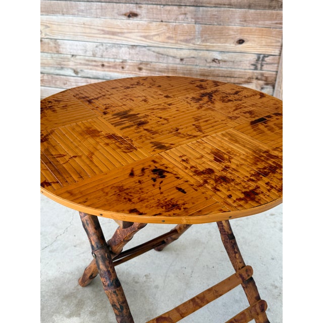 A charming vintage rattan and bamboo folding side table featuring a beautifully constructed slat top and sculptural X-base...