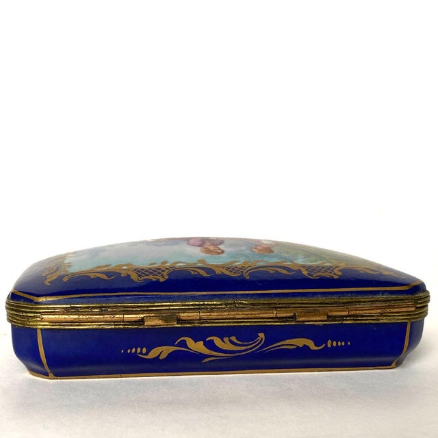 DETAILS An antique porcelain box, of rectangular form with rounded corners and a hinged, slightly domed lid. The lid is...
