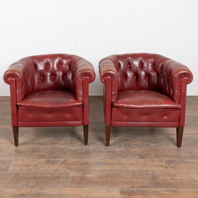 Pair of 20th century Danish club chairs upholstered in red vintage leather. The chairs feature a rounded barrel back with...