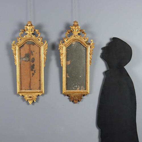 A pair of carved and gilded wooden mirrors. The cymatium is pierced and carved with scrolls, leaves, and cascading flowers...