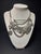 This statement necklace features an antique silver-tone finish with layered chains and assorted charms, including a leaf,...