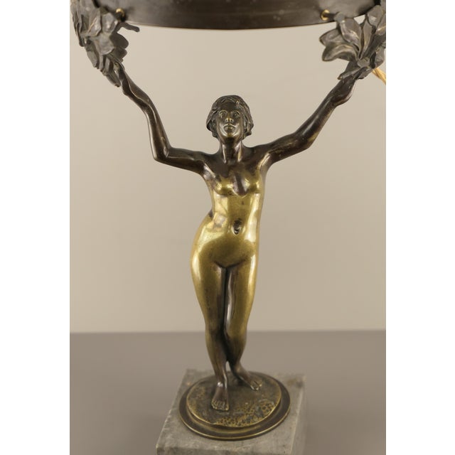The candlestick base, mounted on a marble pedestal, is a fully sculpted representation of Daphne as a female, naked beauty...